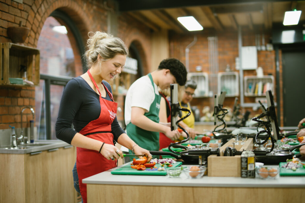 Person preparing vegetables in a hands-on Supper Club at COOK! with the Vegetarian Society