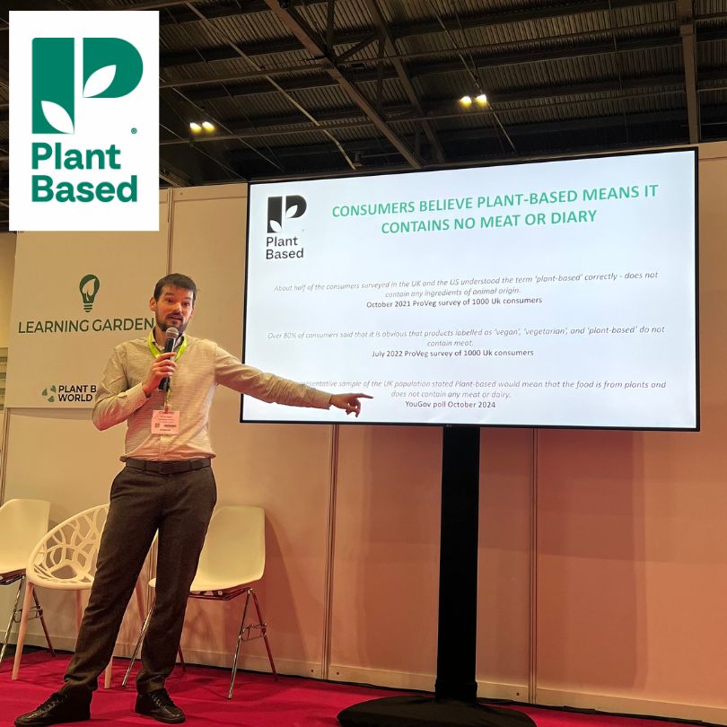 Ben Worth Director of Development, the Vegetarian Society, next to a presentation screen which displays information about the plant-based trademark, at the Plant-Based Expo