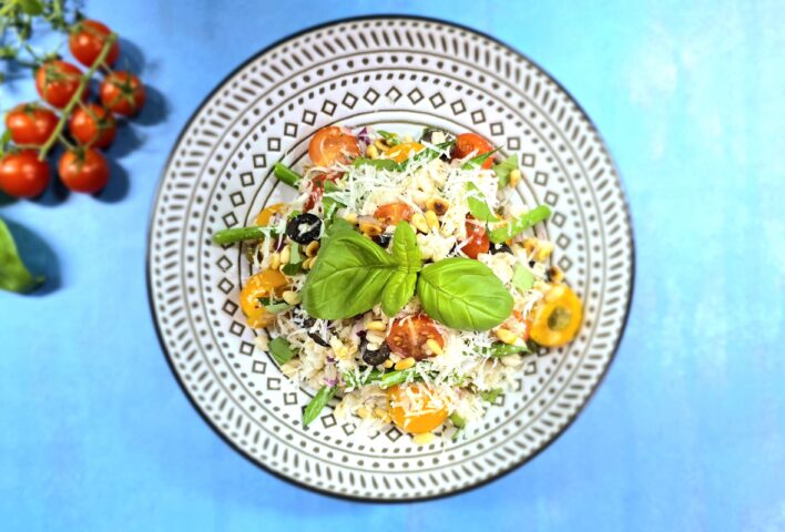 Cherry tomato and barley salad served on a patterned plate, set against a blue background.